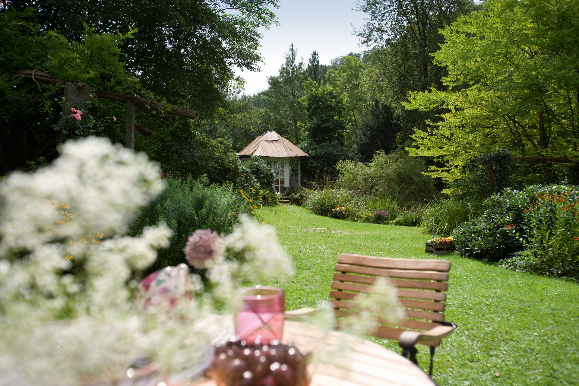 Ogród z zielonym trawnikiem, krzesło na pierwszym planie i taras w oddali