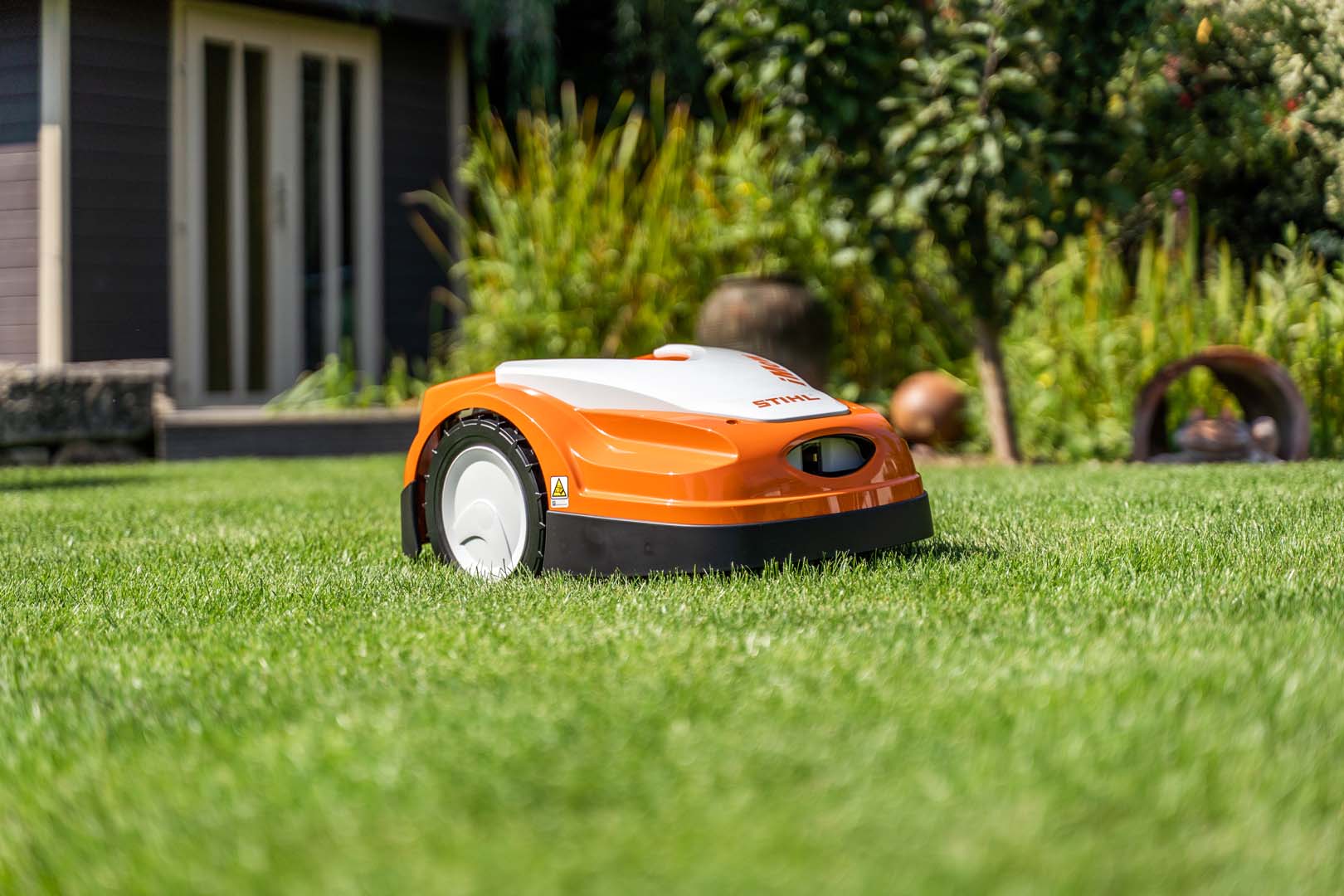 Robot koszący STIHL iMOW® na zielonym trawniku w ogrodzie