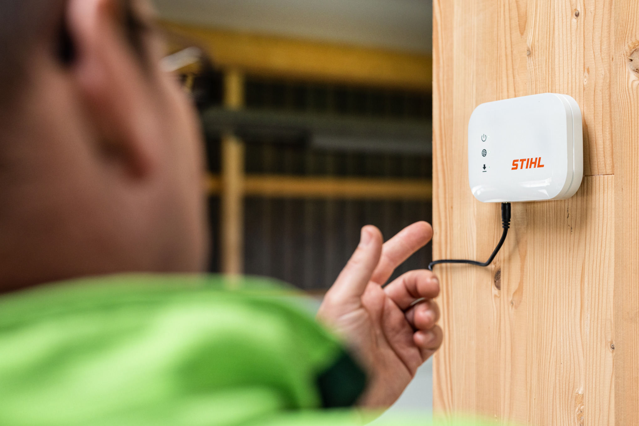 Zbliżenie na osobę wskazującą mobilną skrzynkę STIHL connected