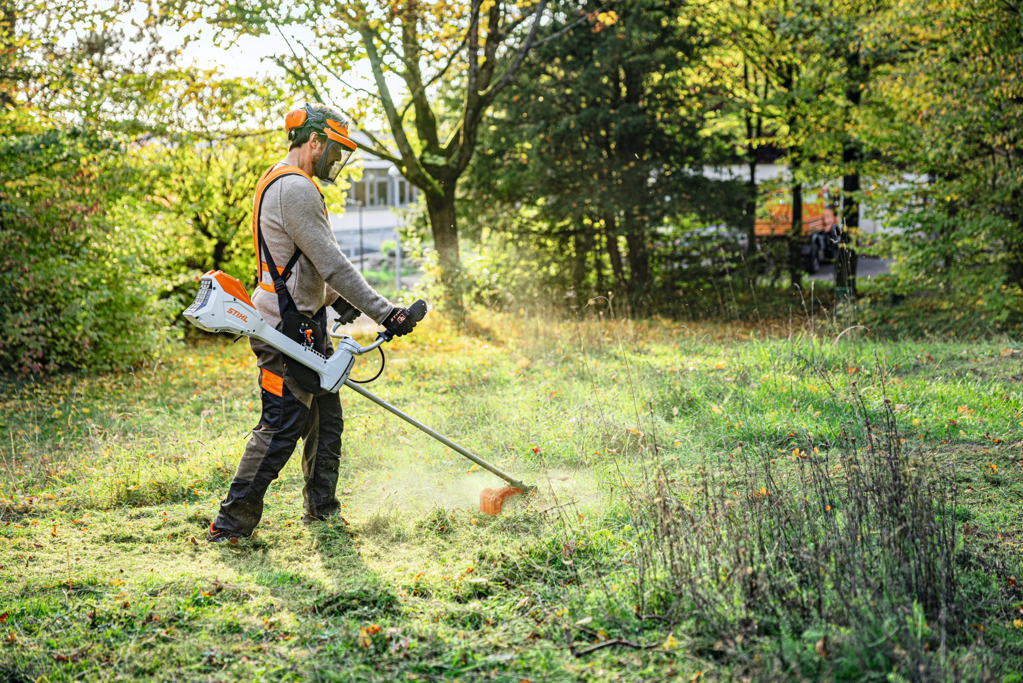Mężczyzna kosi zielony teren w parku akumulatorową kosą mechaniczną STIHL FSA 200 