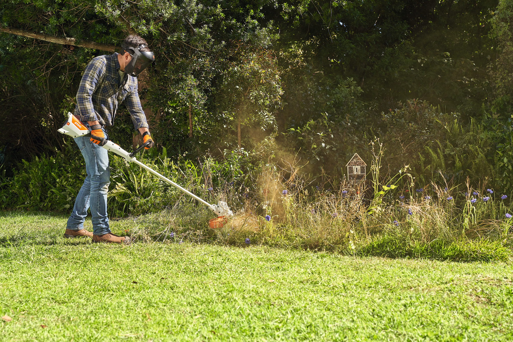 Mężczyzna kosi łąkę z dzikimi kwiatami za pomocą STIHL FSA 57