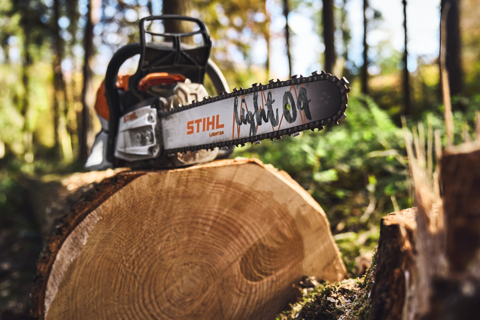 Zbliżenie pilarki łańcuchowej STIHL z prowadnicą light 04 na pniu drzewa w lesie