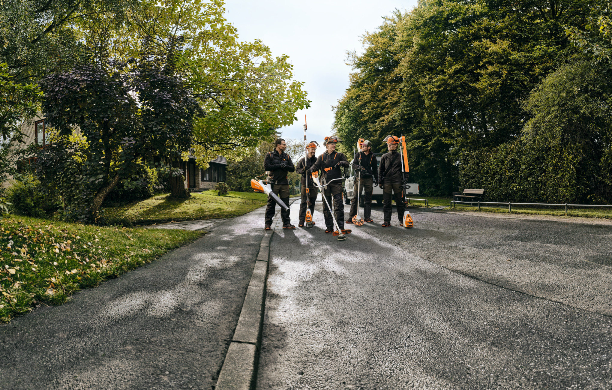 Pięciu profesjonalistów STIHL biegnie ulicą, trzymając urządzenia akumulatorowe