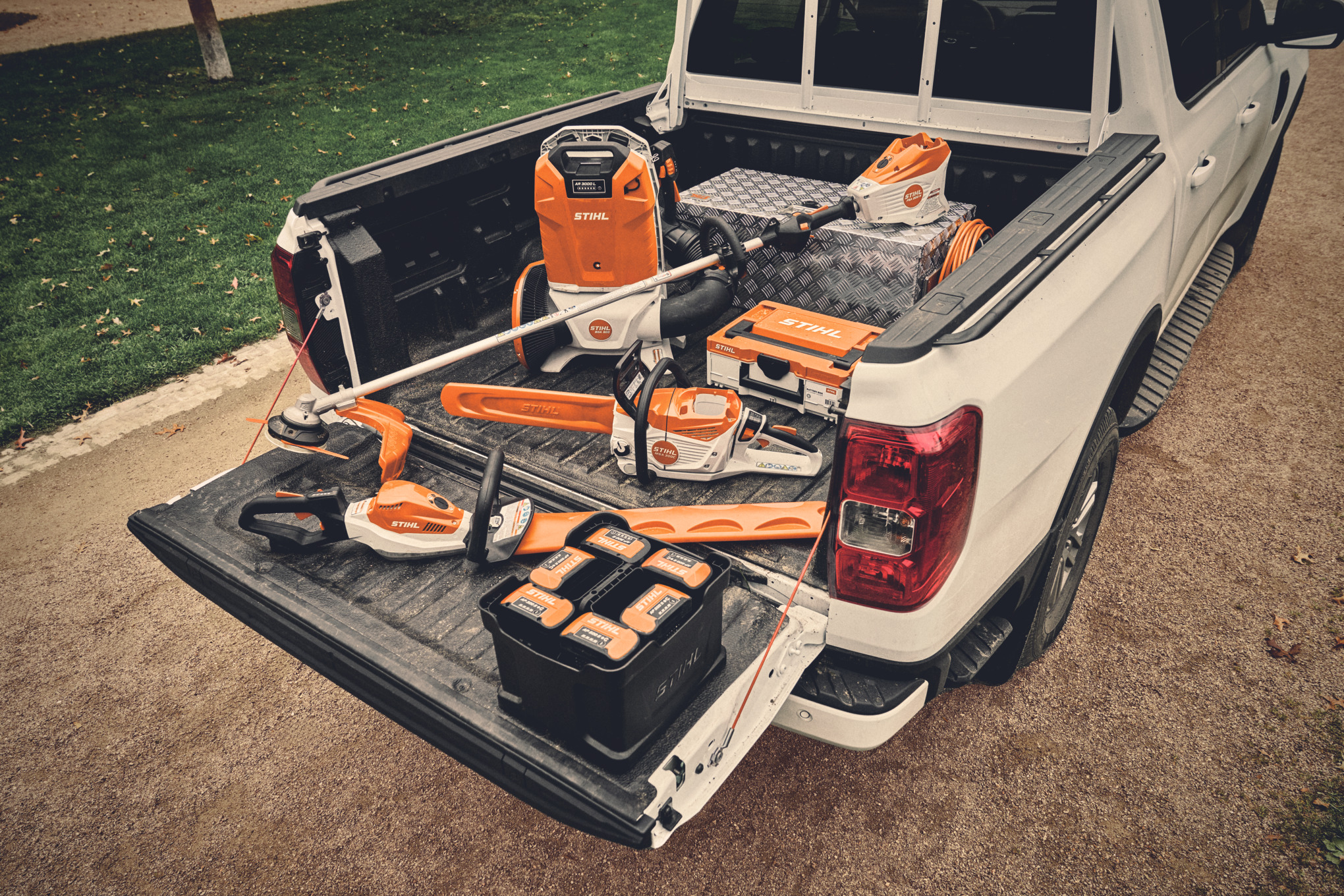 Różne narzędzia akumulatorowe z systemu STIHL AP i pasujące do nich akumulatory na powierzchni ładunkowej pojazdu