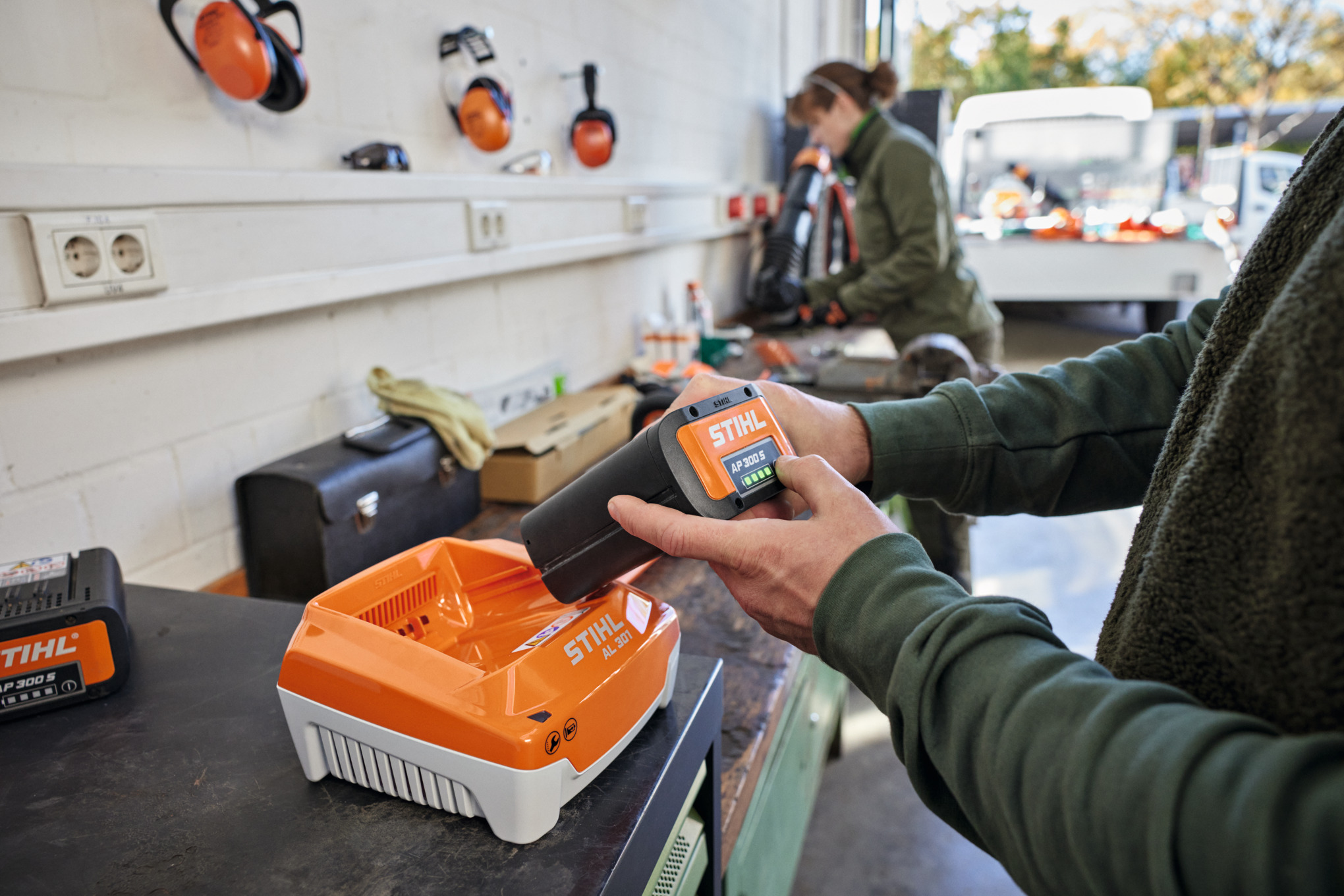  Jedna osoba wkłada akumulator STIHL AP 300 S do szybkiej ładowarki STIHL AL 301