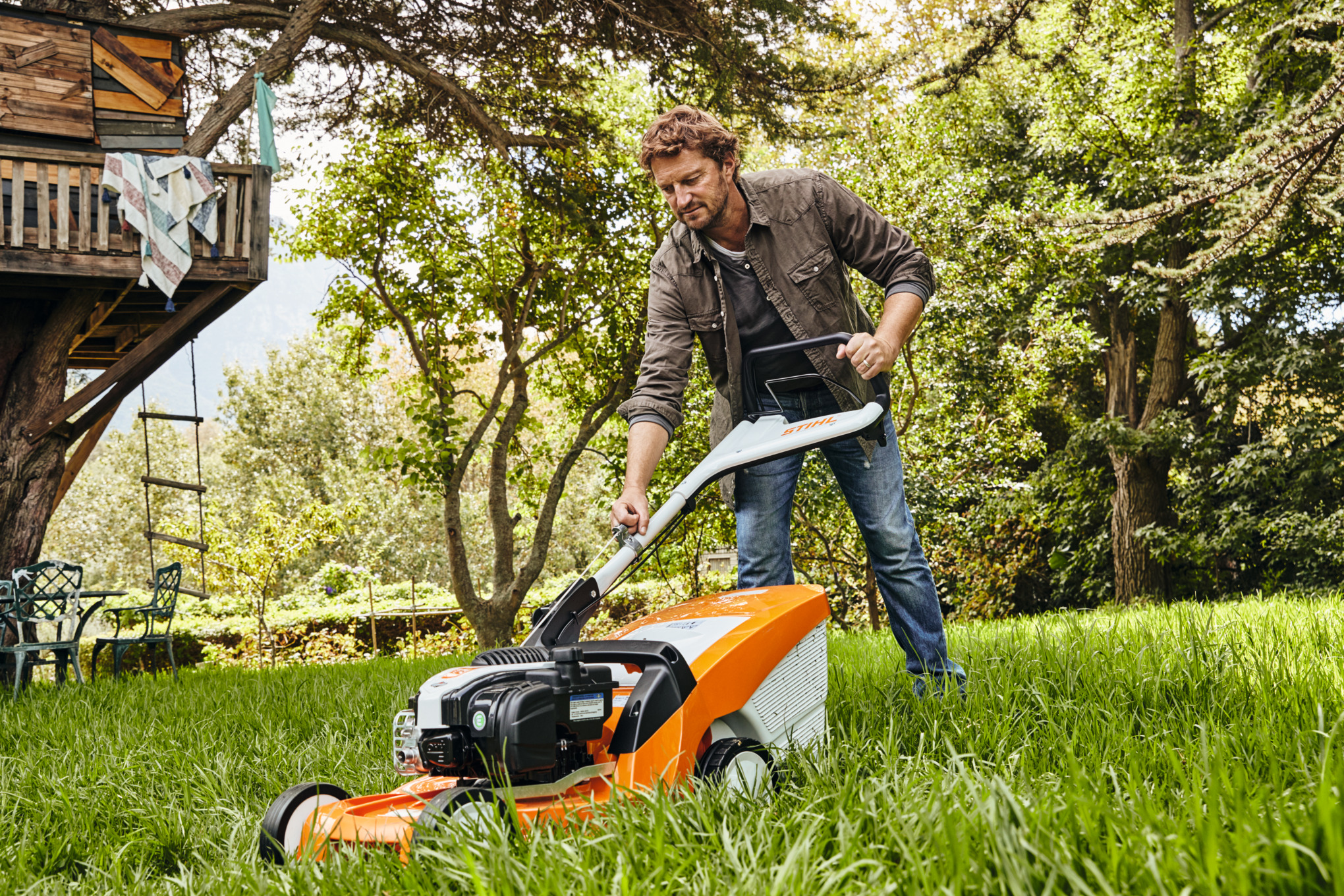 Mężczyzna kosi łąkę ogrodową kosiarką benzynową STIHL RMA 448 TC