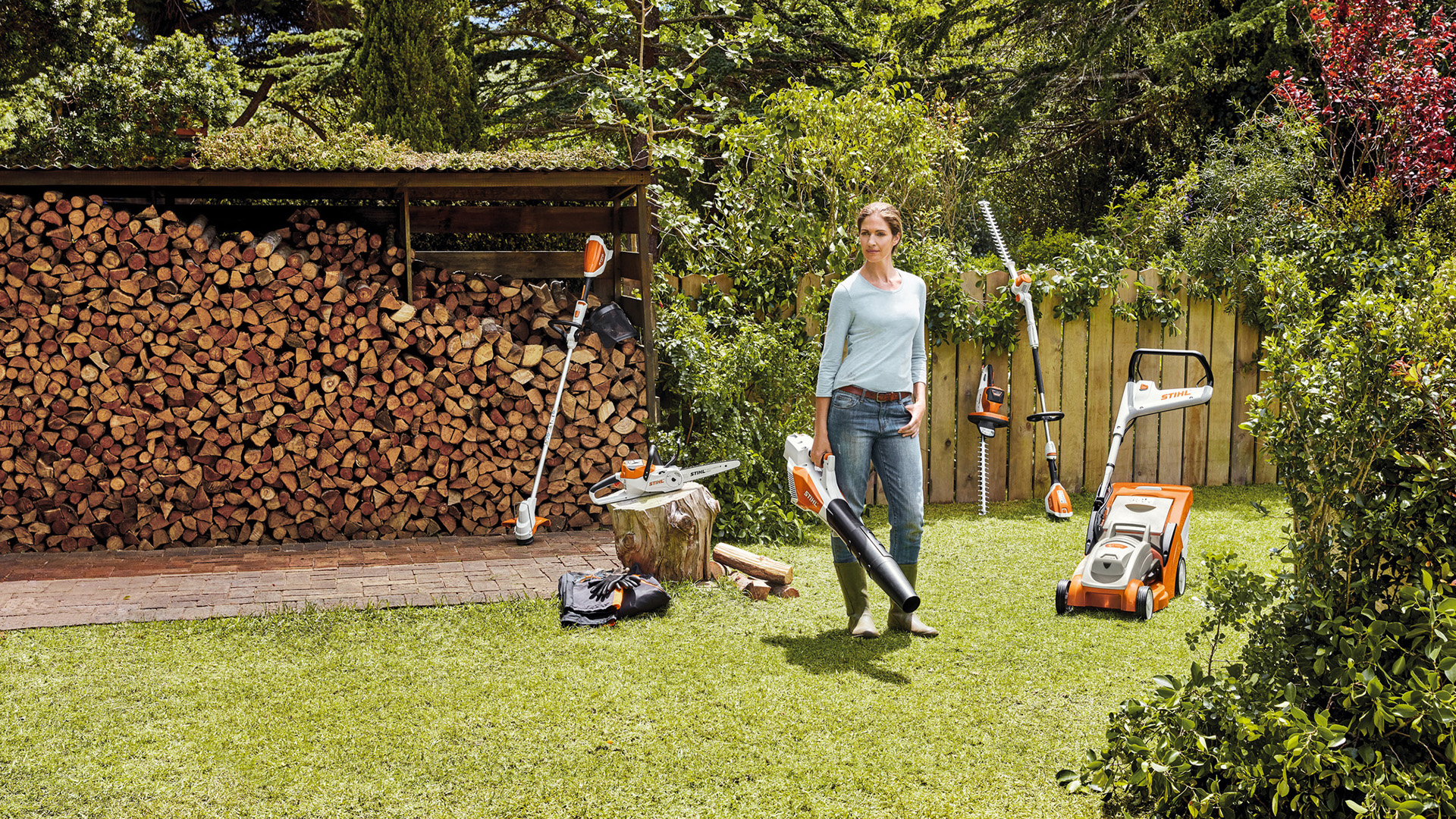 Kobieta stojąca w ogrodzie przed stosem drewna z urządzeniami systemu AK 