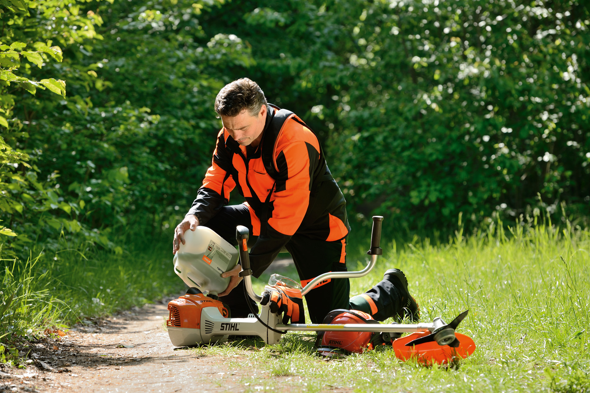 Mężczyzna tankuje kosę mechaniczną STIHL mieszanką benzyny i oleju