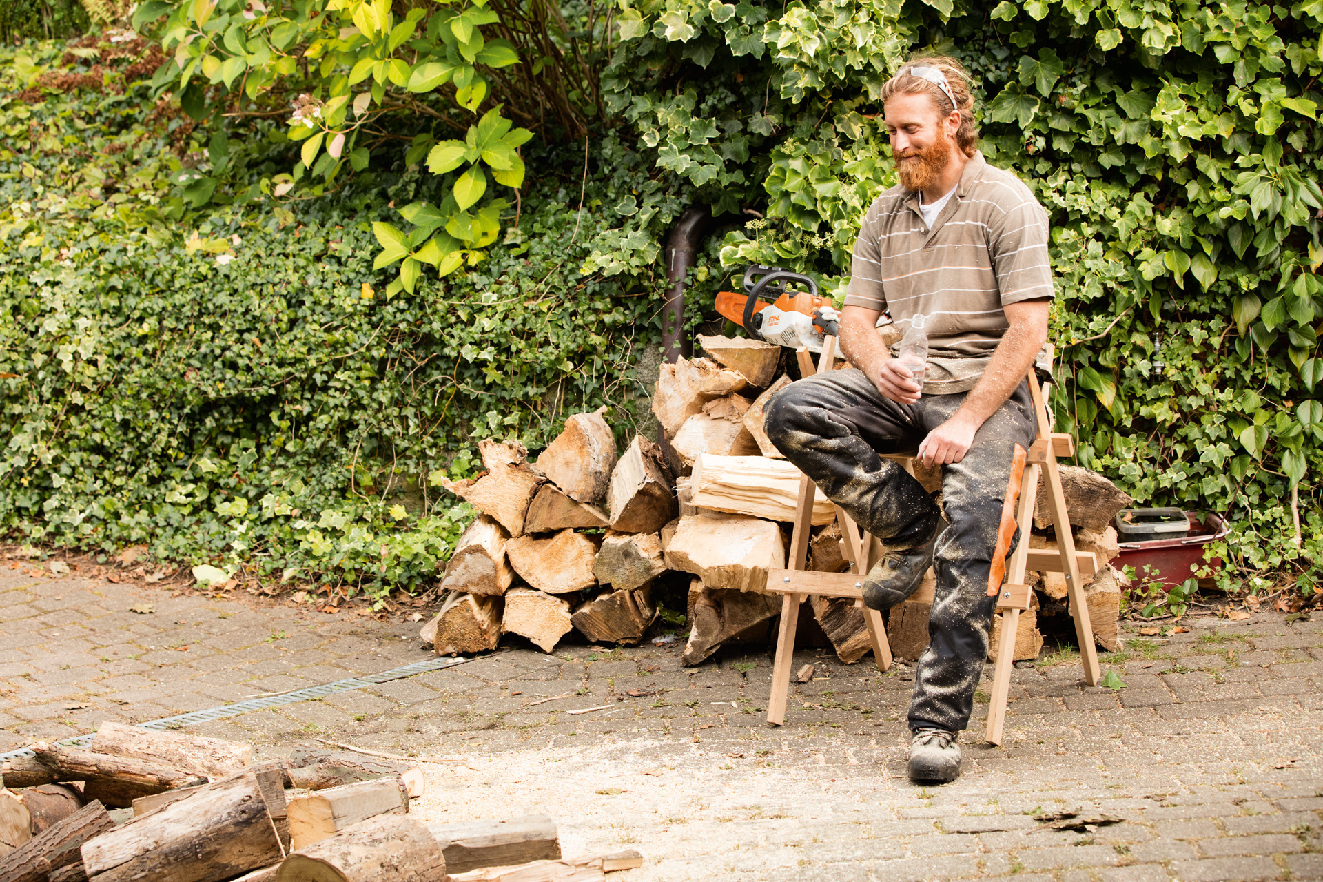 Mężczyzna przy kawałku drewna siedzący na koziołku do cięcia