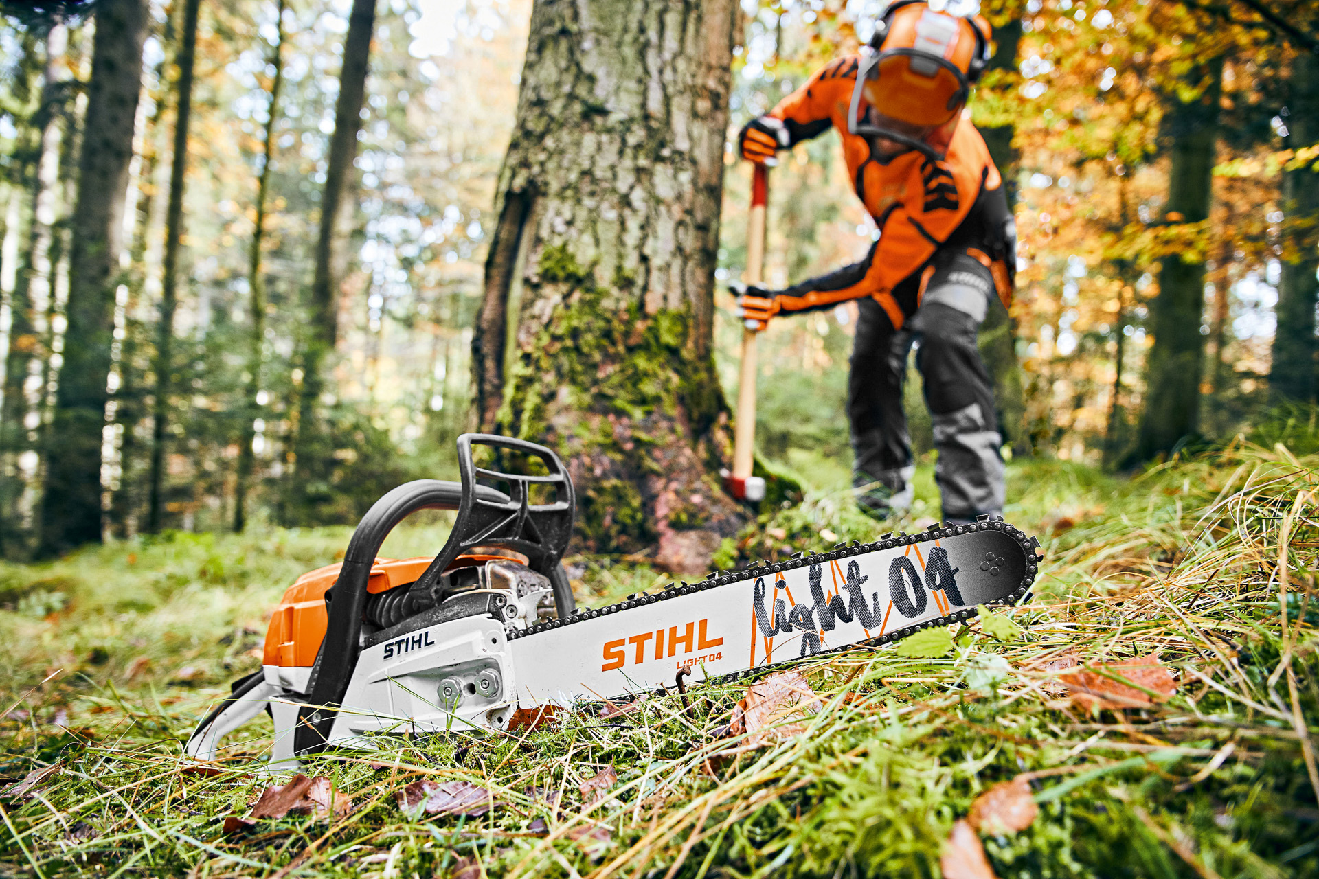 Mężczyzna w stroju ochronnym w lesie, na pierwszym planie piła spalinowa STIHL MS 261 C-M z prowadnicą Light 04