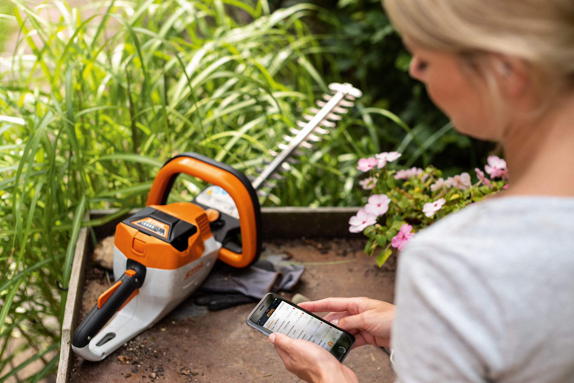 Kobieta rejestruje nożyce do żywopłotu STIHL za pomocą aplikacji STIHL na smartfonie