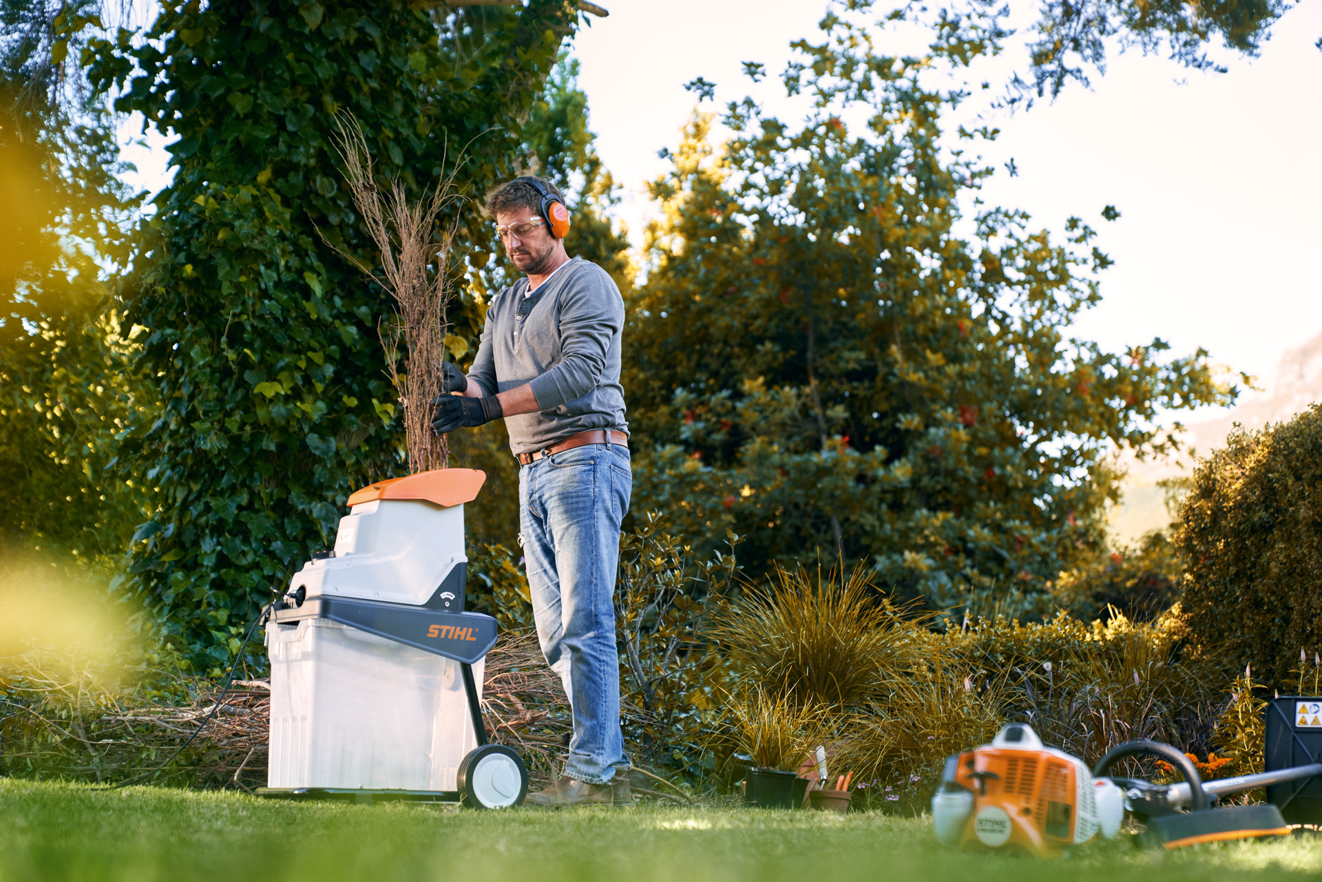 Mężczyzna w ochronnikach słuchu korzystający z rozdrabniacza elektrycznego  STIHL GHE 140 w ogrodzie