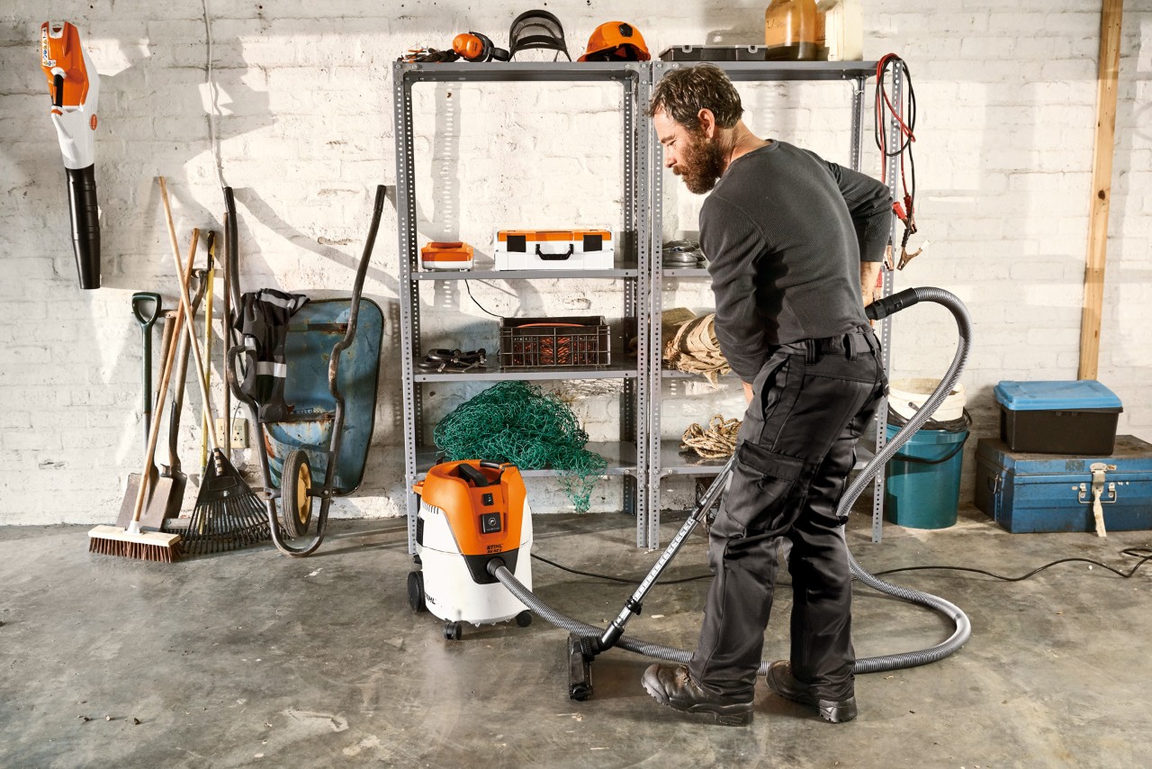 Mężczyzna odkurza podłogę w garażu za pomocą odkurzacza na mokro i sucho STIHL SE 62 E